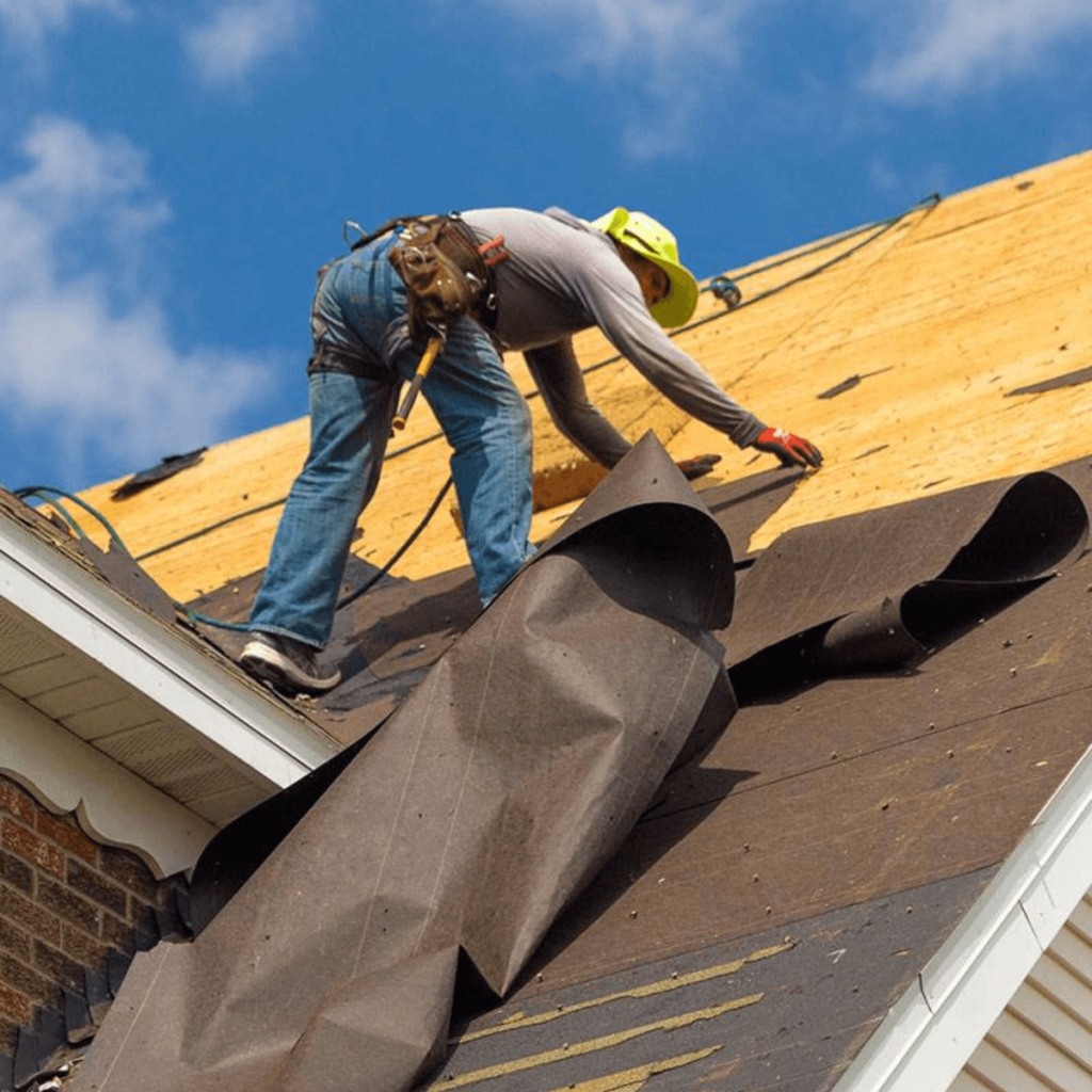 Crew installing asphalt shingles on a residential roof during replacement in Colorado.